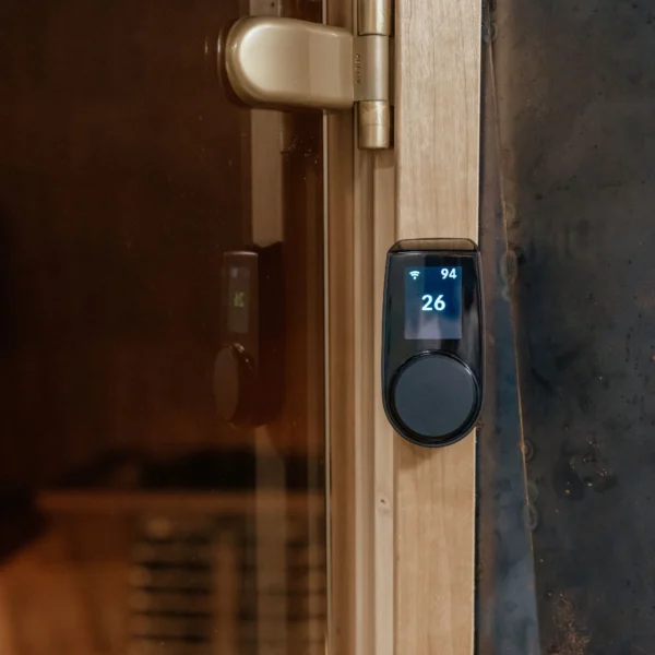 HUUM Wi-Fi Classic Black juhtpaneel, paigaldatud puidust sauna ukse raami külge, temperatuuriks kuvatakse 26°C.