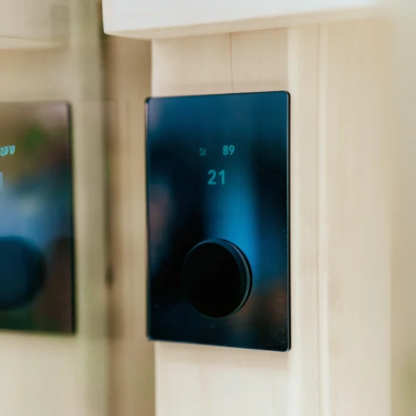 HUUM Wi-Fi Glass Black juhtpaneel, millel kuvatakse temperatuur 21°C kaasaegse puidust sauna interjööris.