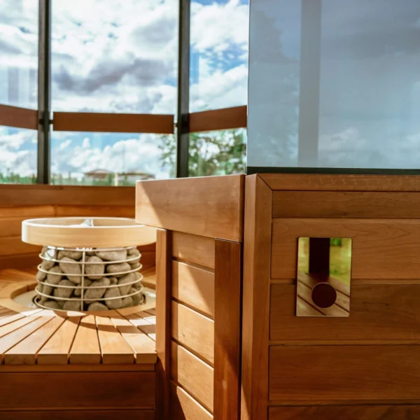 Sauna interior with a wooden finish and a modern HUUM heater surrounded by stones.