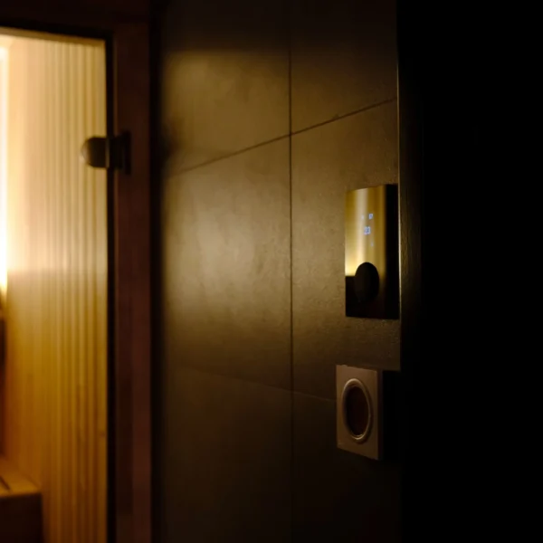 HUUM Local Gold control panel illuminated in a dimly lit sauna setting.