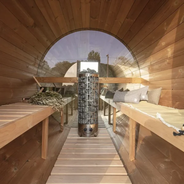 Interior of wooden barrel sauna with mirrored end panels and heater.