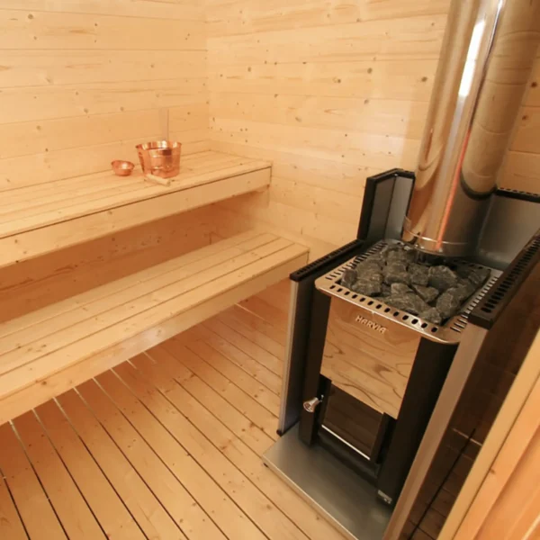 Sauna interior with a Harvia wood-burning stove, stainless steel chimney, benches, and sauna accessories.