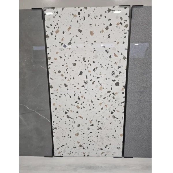 A close-up view of three large porcelain tile slabs displayed upright. The central tile is white with a dotted pattern.