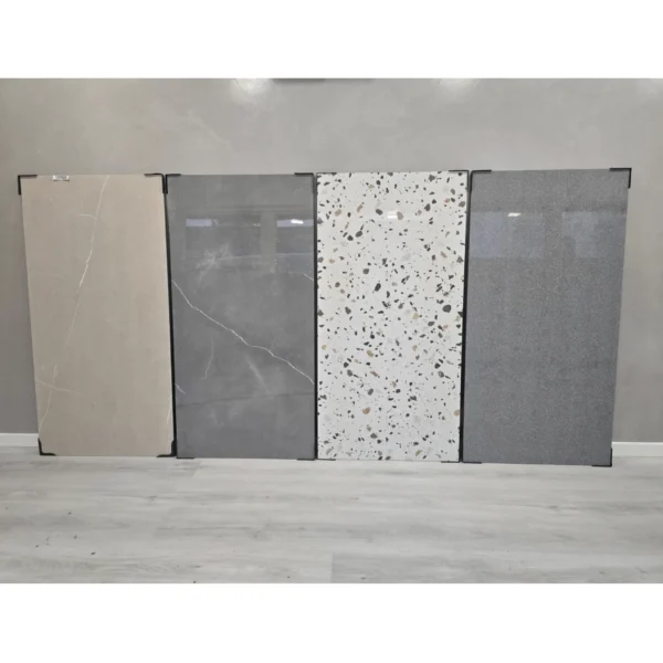 Four large porcelain tile slabs displayed upright in a row. The tiles showcase different colors and patterns.